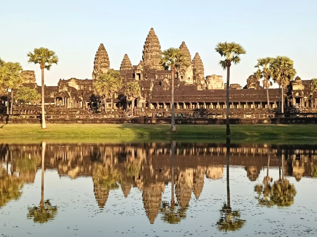 Vista panoramica del tempio di Angkor Wat all'alba con riflesso nell'acqua, guida italiana spiega la storia ai turisti