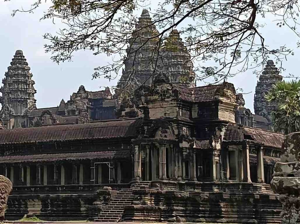 Guida turistica italiana che assiste un viaggiatore con la macchina fotografica al tempio di Angkor Wat